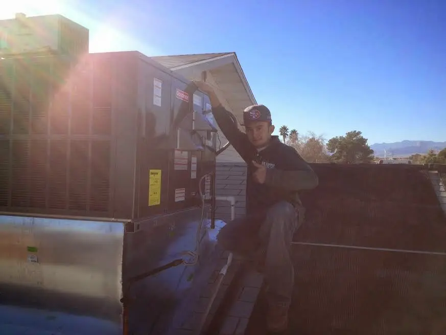 HVAC technician performing Air Duct Cleaning on a rooftop unit in Williamsburg